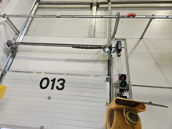 Albero con molla a torsione sopra una porta sezionale industriale – sostituzione molle porta sezionale a Polverara
