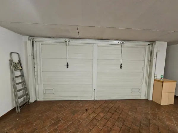 Basculante a due ante vista dall'interno del garage, con bracci e serrature – riparazione basculanti ad Agna