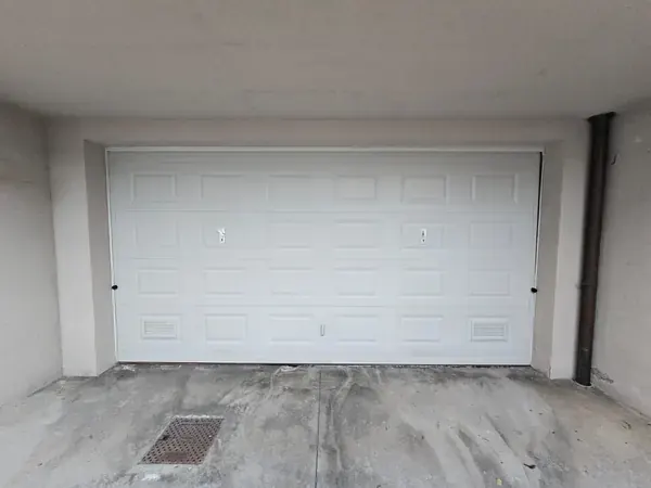 Porta sezionale bianca di un garage doppio – sostituzione molle porta sezionale a Pernumia