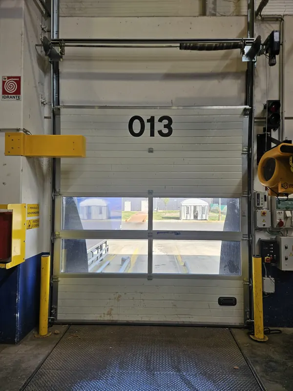 Porta sezionale industriale con finestrature su una baia di carico – sostituzione molle porta sezionale a Pernumia